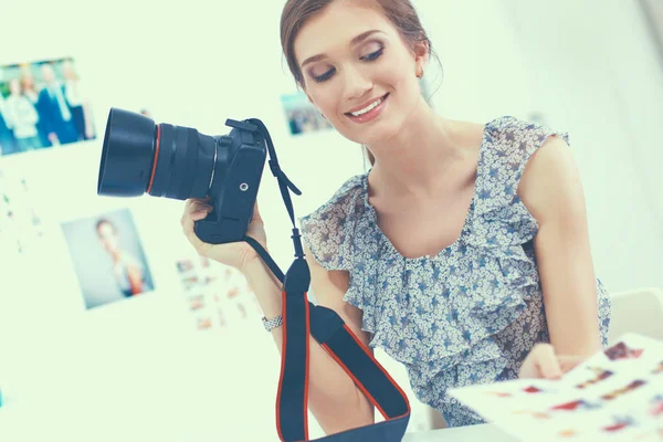 Молодая женщина-фотограф обрабатывает фотографии, сидя на столе — стоковое фото