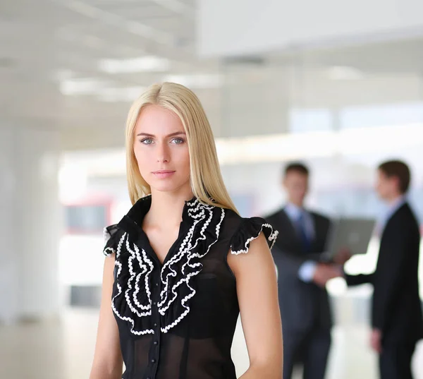 Business woman standing in foreground in office — Stock Photo, Image