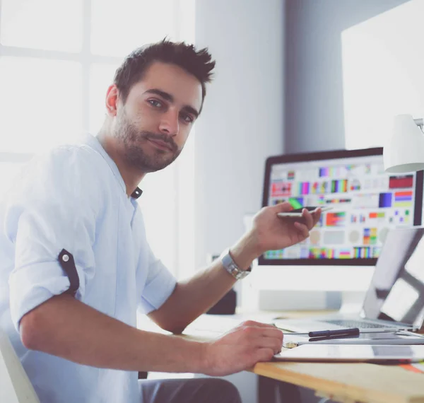 Porträt eines jungen Designers, der im Grafikstudio vor Laptop und Computer sitzt, während er online arbeitet. — Stockfoto