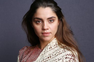 Bej örgü eşarp takan bir kadın.