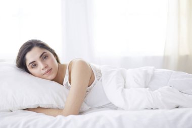 Güzel bir kadın yatağında uzanıyor.