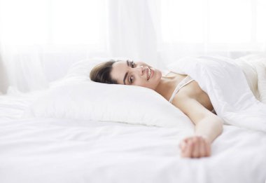 Güzel bir kadın yatağında uzanıyor.