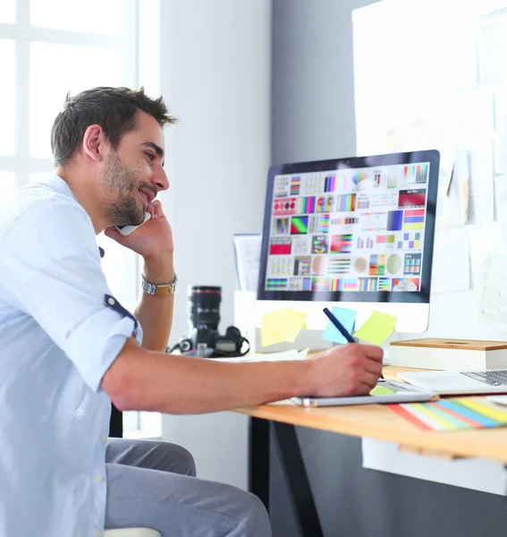 Porträt eines jungen Designers, der im Grafikstudio vor Laptop und Computer sitzt, während er online arbeitet. — Stockfoto