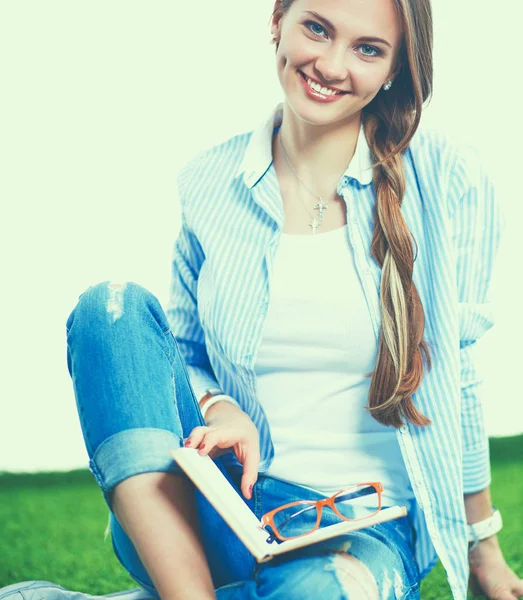 Jonge vrouw zitten met boek op gras — Stockfoto