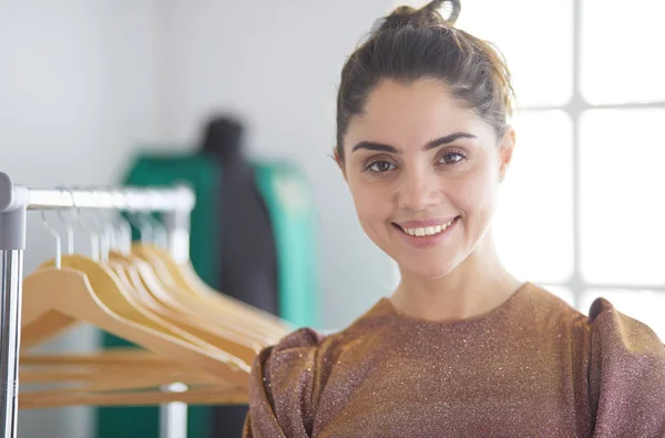 Mooie jonge stylist bij rek met hangers — Stockfoto