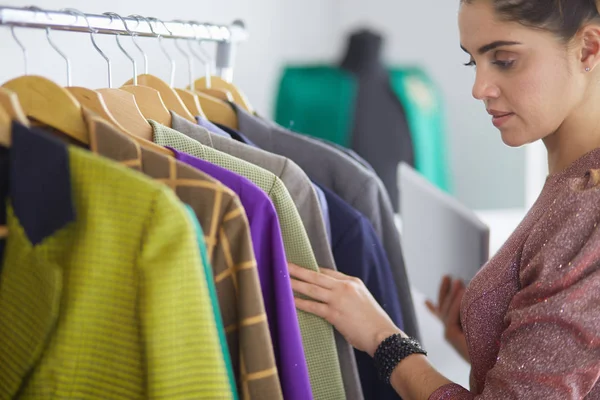 Schöne junge Stylistin in der Nähe von Gestell mit Kleiderbügeln — Stockfoto