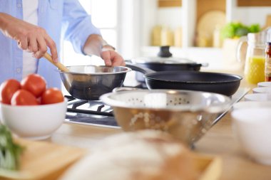 Adam ev mutfağında lezzetli ve sağlıklı yemekler hazırlıyor.