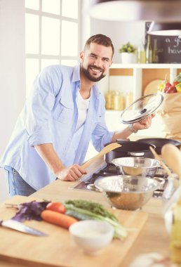 Adam ev mutfağında lezzetli ve sağlıklı yemekler hazırlıyor.