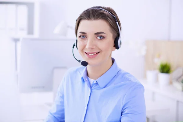 Ernstige mooie jonge vrouw die werkt als support telefoon operator met headset in het kantoor — Stockfoto