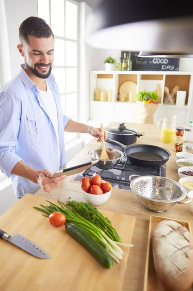Homem seguindo receita em tablet digital e cozinhar comida saborosa e saudável na cozinha em casa — Fotografia de Stock