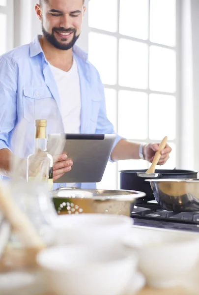 Hombre siguiendo la receta en la tableta digital y cocinar comida sabrosa y saludable en la cocina en casa — Foto de Stock