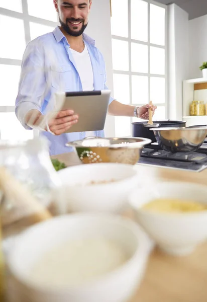 Hombre siguiendo la receta en la tableta digital y cocinar comida sabrosa y saludable en la cocina en casa — Foto de Stock