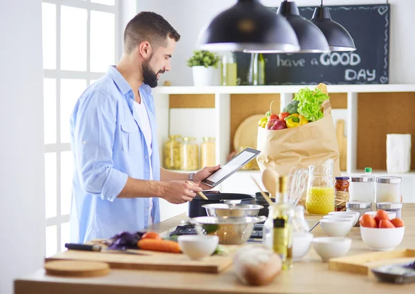 Mann folgt Rezept auf digitalem Tablet und kocht leckeres und gesundes Essen in der heimischen Küche — Stockfoto