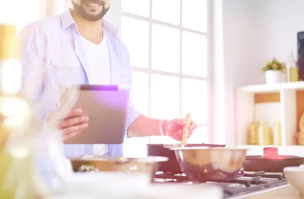 Hombre siguiendo la receta en la tableta digital y cocinar comida sabrosa y saludable en la cocina en casa — Foto de Stock