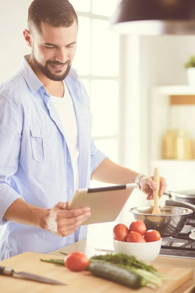 Dijital tablet ve yemek pişirme tarifine uyan bir adam evdeki mutfakta lezzetli ve sağlıklı yemekler pişiriyor. — Stok fotoğraf