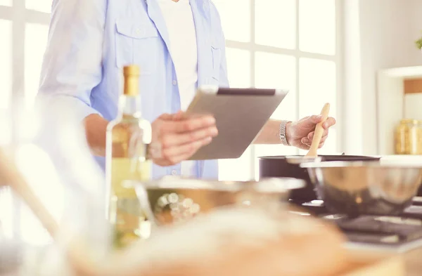 Manusia mengikuti resep pada tablet digital dan memasak makanan lezat dan sehat di dapur di rumah — Stok Foto