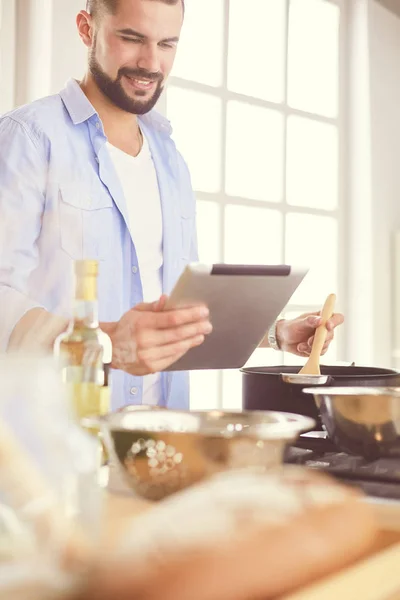 Dijital tablet ve yemek pişirme tarifine uyan bir adam evdeki mutfakta lezzetli ve sağlıklı yemekler pişiriyor. — Stok fotoğraf