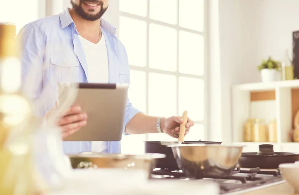 Dijital tablet ve yemek pişirme tarifine uyan bir adam evdeki mutfakta lezzetli ve sağlıklı yemekler pişiriyor. — Stok fotoğraf