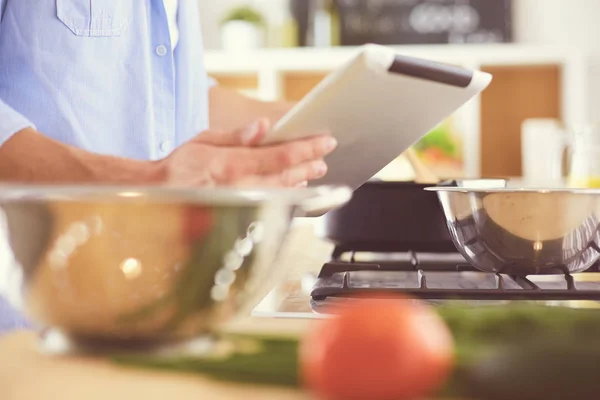 Man following recipe on digital tablet and cooking tasty and healthy food in kitchen at home — Stock Photo, Image