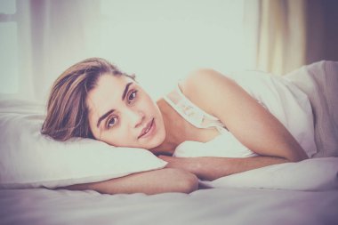 Güzel bir kadın yatağında uzanıyor.