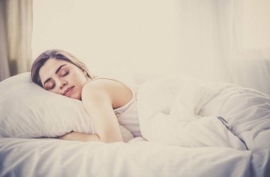 Güzel bir kadın yatağında uzanıyor.