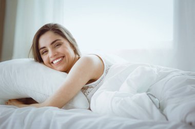 Güzel bir kadın yatağında uzanıyor.