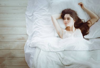 Güzel bir kadın yatağında uzanıyor.