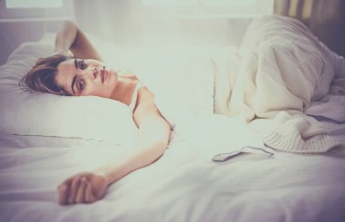 Güzel bir kadın yatağında uzanıyor.