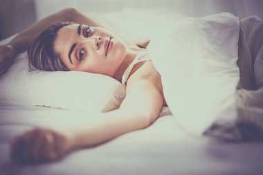 Güzel bir kadın yatağında uzanıyor.
