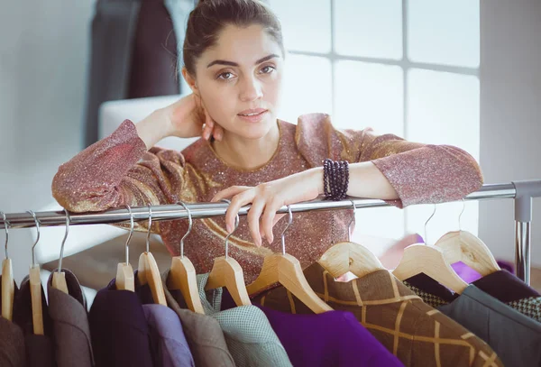 Mooie jonge stylist bij rek met hangers — Stockfoto