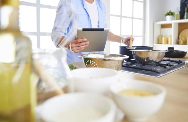 Man following recipe on digital tablet and cooking tasty and healthy food in kitchen at home — Stock Photo, Image