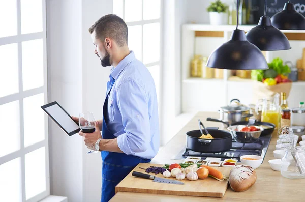 Man efter recept på digital tablett och matlagning välsmakande och hälsosam mat i köket hemma — Stockfoto