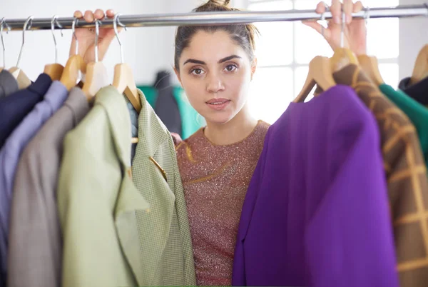 Bella giovane stilista vicino rack con appendini — Foto Stock