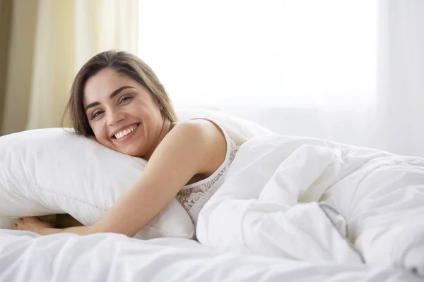 Pretty woman lying down on her bed at home