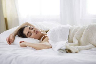 Güzel bir kadın yatağında uzanıyor.