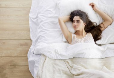 Güzel bir kadın yatağında uzanıyor.