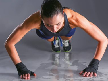 Paspasın üzerinde şınav çeken genç bir kadın..