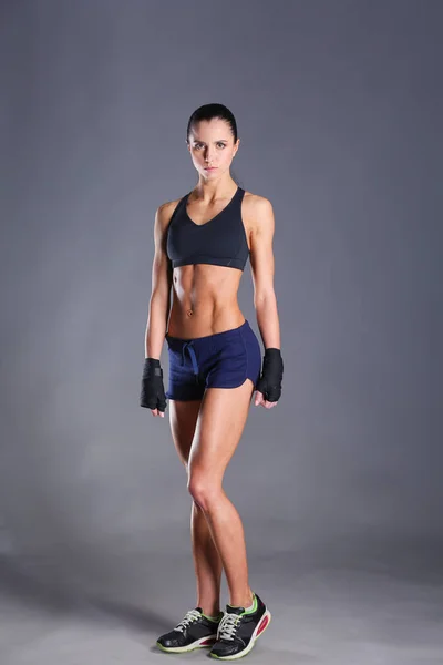 Muskulöse junge Frau posiert in Sportbekleidung vor schwarzem Hintergrund — Stockfoto