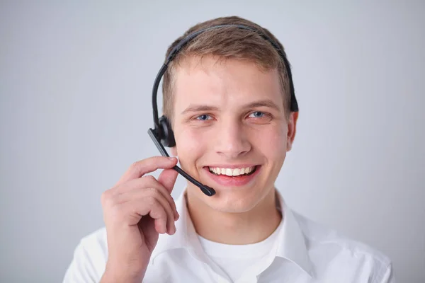 Portret van de jonge man die lacht zittend op een grijze achtergrond. Portret van jonge man — Stockfoto