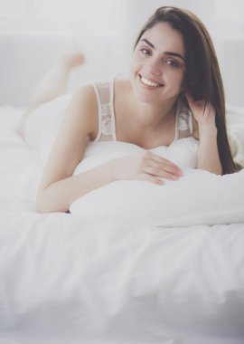 Güzel bir kadın yatağında uzanıyor.