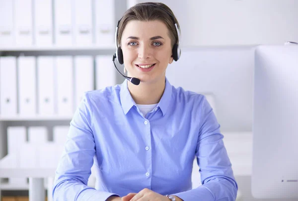 Sério muito jovem mulher trabalhando como operador de telefone de apoio com fone de ouvido no escritório — Fotografia de Stock