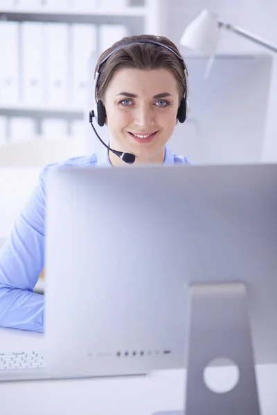 Ernstige mooie jonge vrouw die werkt als support telefoon operator met headset in het kantoor — Stockfoto