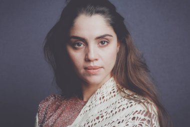 Bej örgü eşarp takan bir kadın.