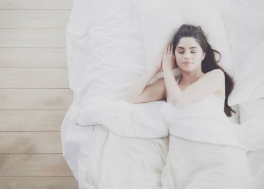 Güzel bir kadın yatağında uzanıyor.