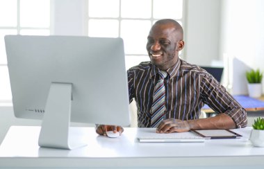 Yakışıklı Afro Amerikalı işadamı Klasik takım elbiseli bir dizüstü bilgisayar kullanarak ve ofiste çalışırken gülümseyen