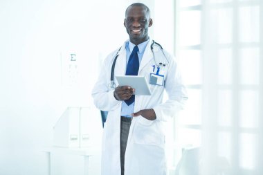 Tablet bilgisayarlı siyahi bir doktor hastanede bekliyor.