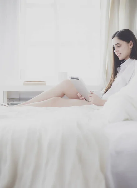 Mulher sentada na cama lendo um livro e tomando café da manhã — Fotografia de Stock