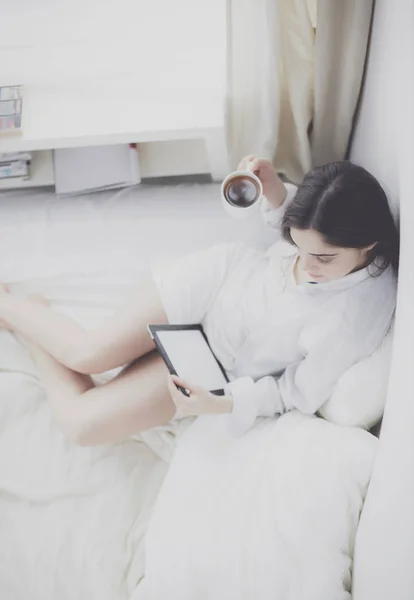 早上坐在床上用石碑和咖啡的女人的画像 — 图库照片