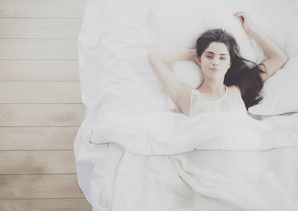 Pretty woman lying down on her bed at home — Stock Photo, Image