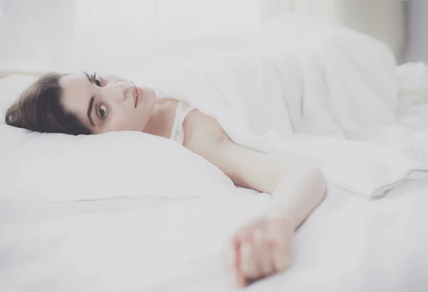 Pretty woman lying down on her bed at home